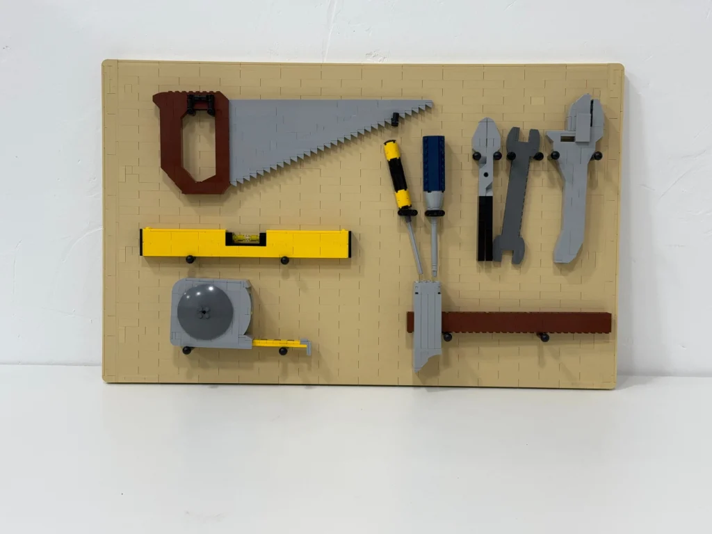 A tool holder made from LEGO that features a handsaw, a level, a tape measure, pliers, a hammer, and screwdrivers. 