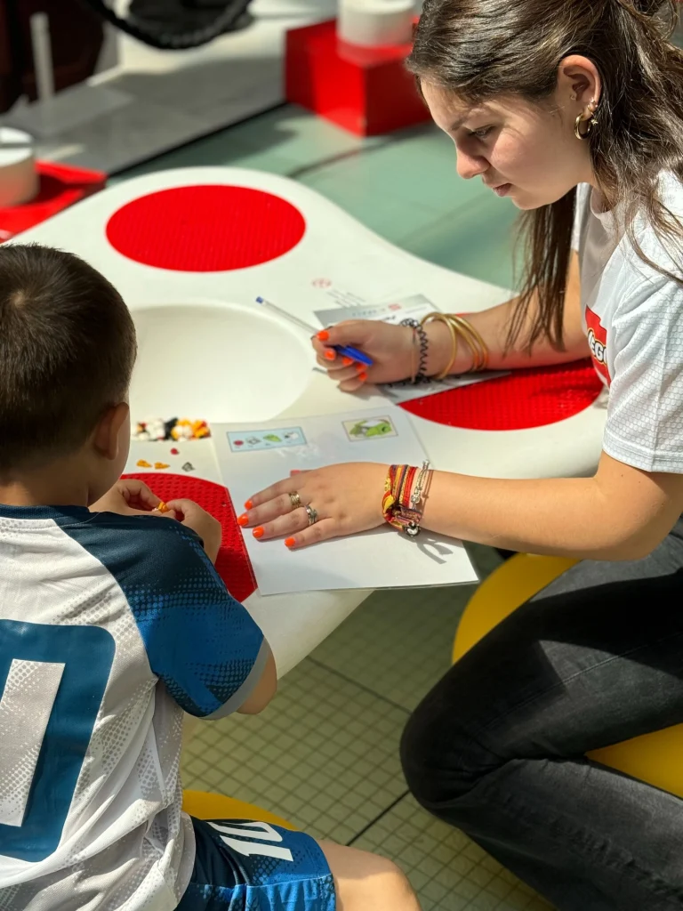 Monitora dando instrucciones de montaje a un asistente al taller LEGO Construye tu nave