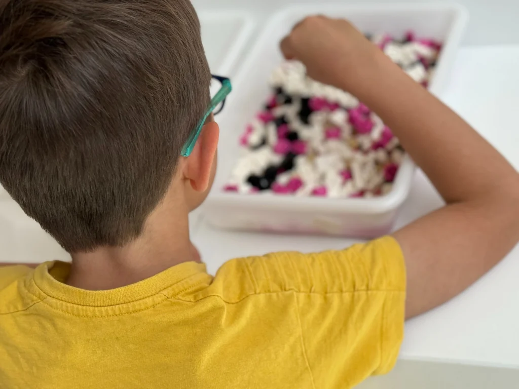Vista posterior de un niño cogiendo piezas de un recipiente para realizar la actividad LEGO Construye tu nave