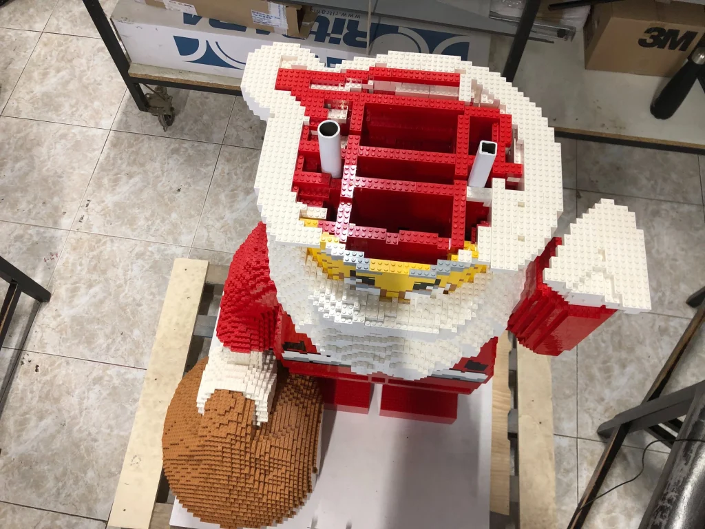Imagen superior de proceso de montaje de escultura de Papá Noel construida con LEGO para ser expuesta en IFEMA durante la Navidad de 2023
