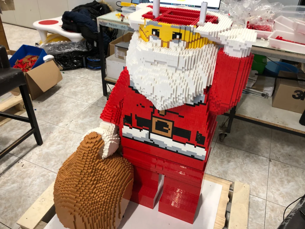 Imagen frontal de proceso de montaje de escultura de Papá Noel construida con LEGO para ser expuesta en IFEMA durante la Navidad de 2023