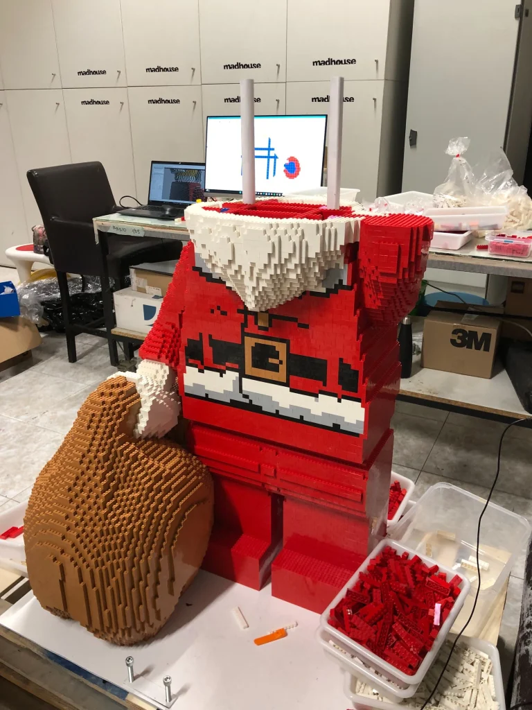 Imagen lateral de proceso de montaje de escultura de Papá Noel construida con LEGO para ser expuesta en IFEMA durante la Navidad de 2023