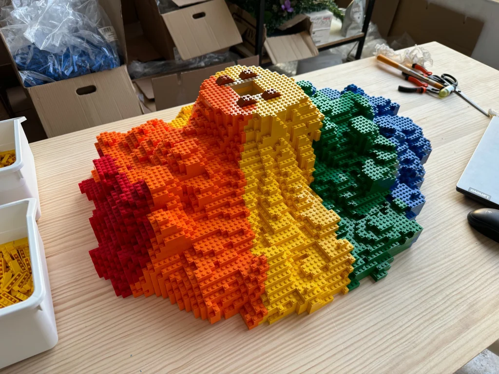 Details of the construction process for the base of the multicolored “Bear and Strawberry Tree” sculpture made with LEGO