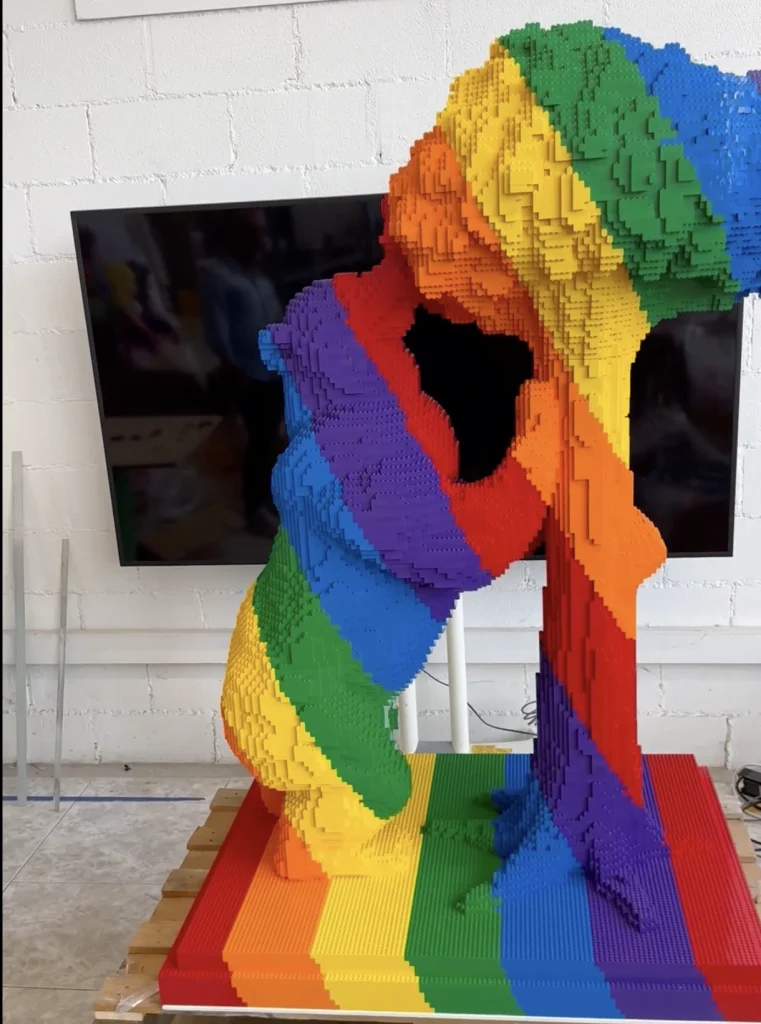 A multicolored sculpture of a bear and a strawberry tree made from LEGO is almost finished.
