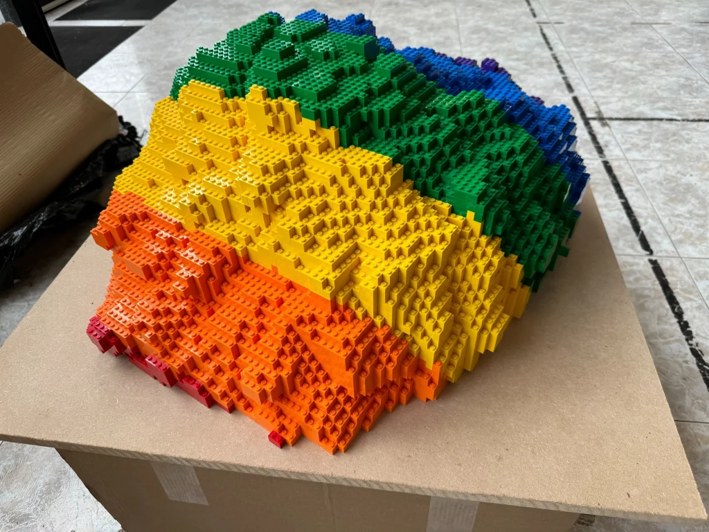 A detailed look at the construction process for the upper part of the multicolored “Bear and Strawberry Tree” sculpture made with LEGO