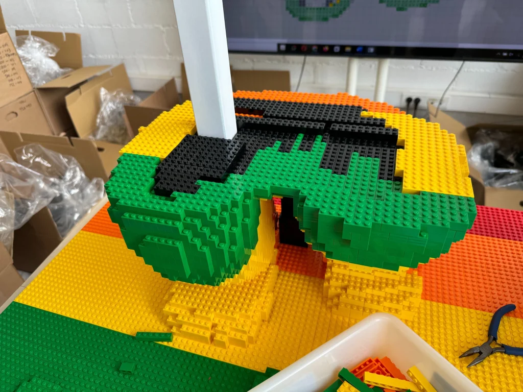 Side view showing the construction process of the base for the multicolored “Bear and Strawberry Tree” sculpture made with LEGO