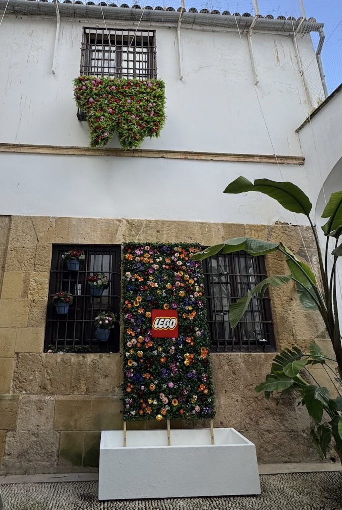 A window with a hanging garden and a wall of flowers built with LEGO for the Patios Festival in Córdoba.