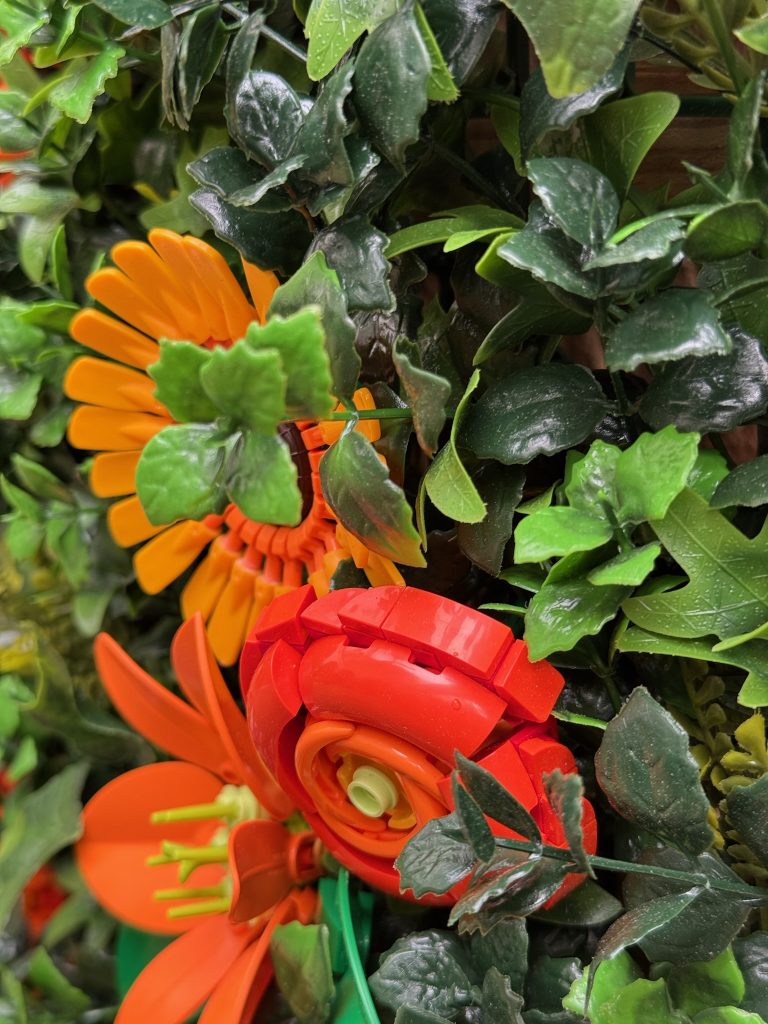Close-up of a sunflower, buttercup, and lily on a flower wall built with LEGO