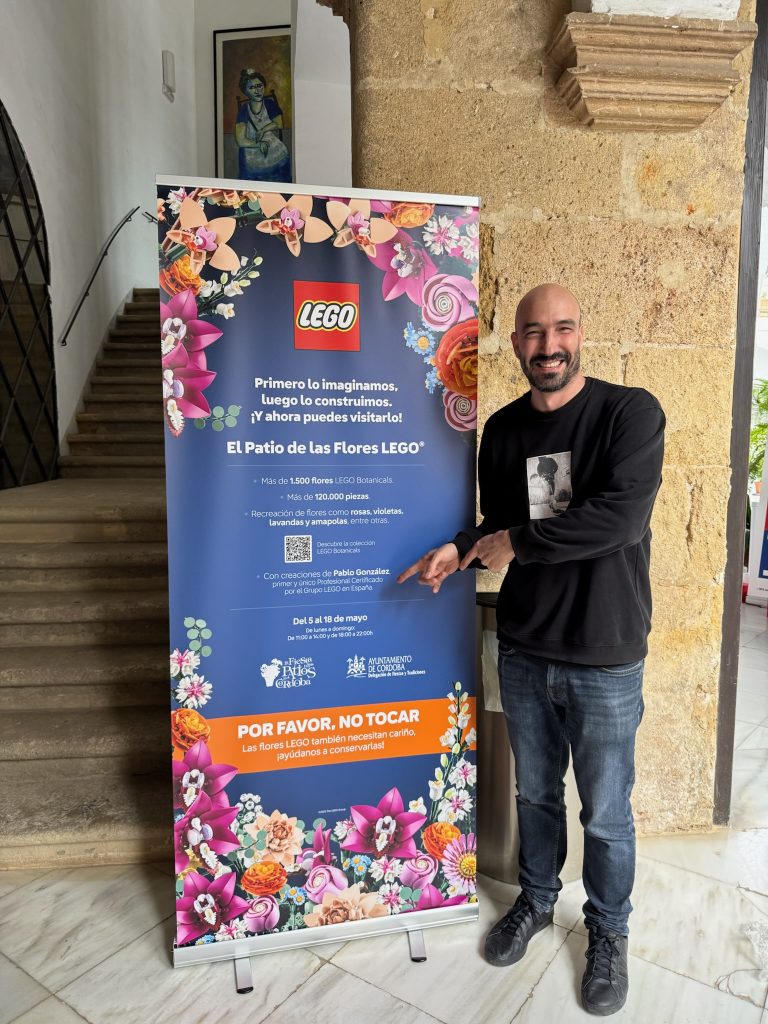 Pablo González stands next to the poster advertising the LEGO flower courtyard, designed and built for the Patios de Córdoba festival. 
