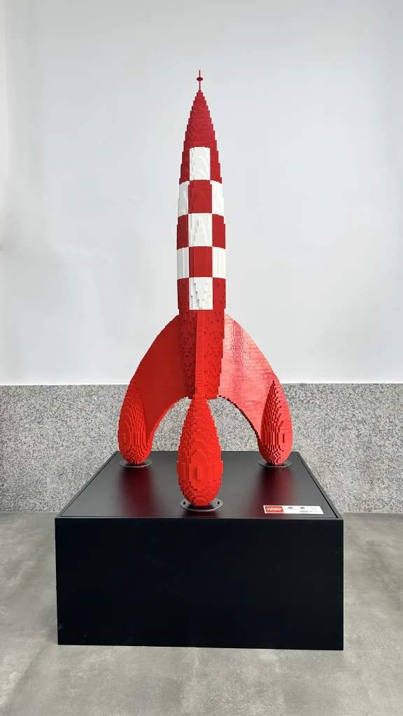 Escultura cohete Tintín construida con LEGO sobre soporte de madera